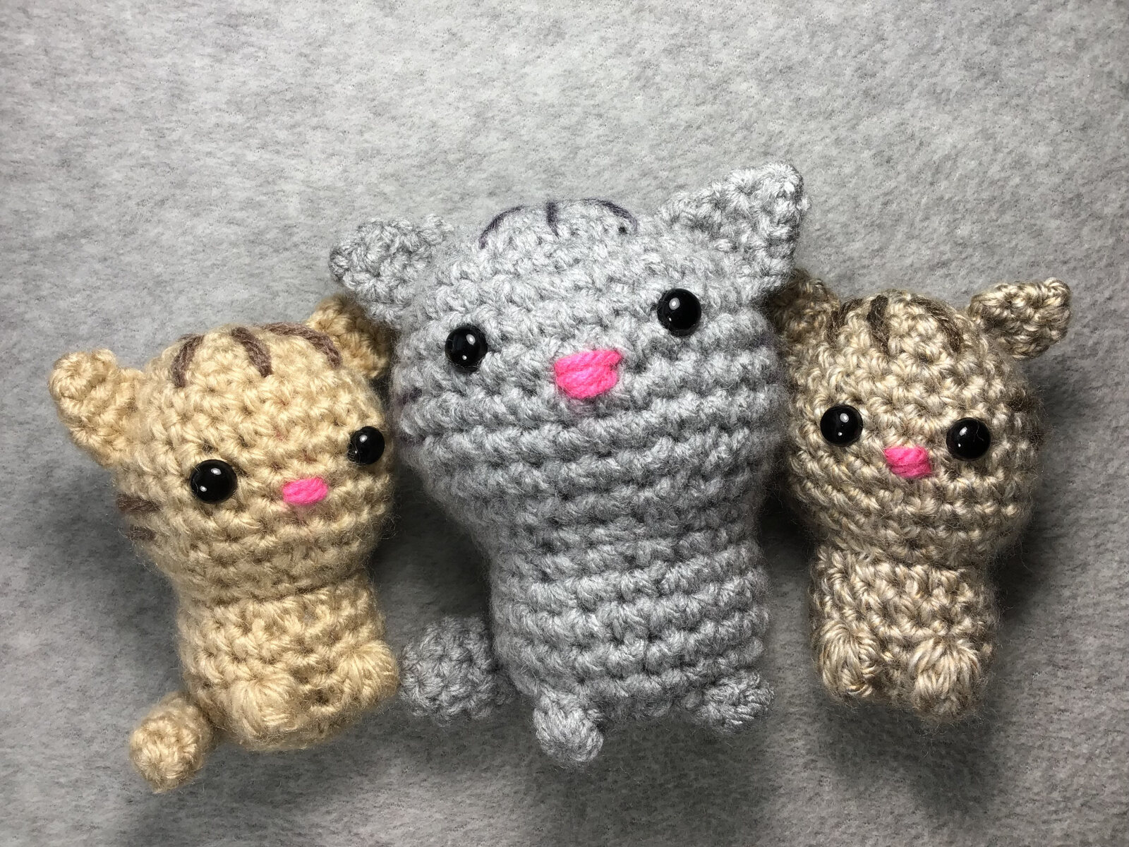 Three small crocheted kittens in gray and tan