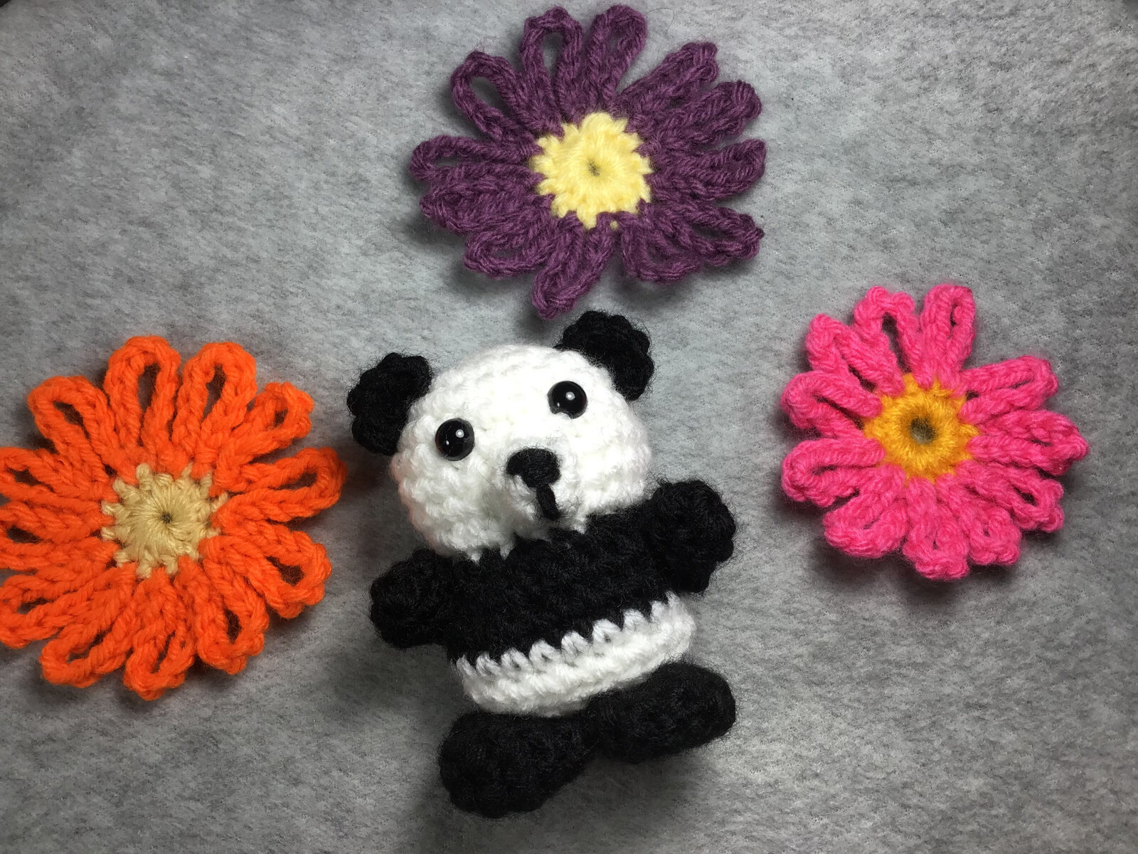 Small crocheted panda surrounded by colorful crochet flowers