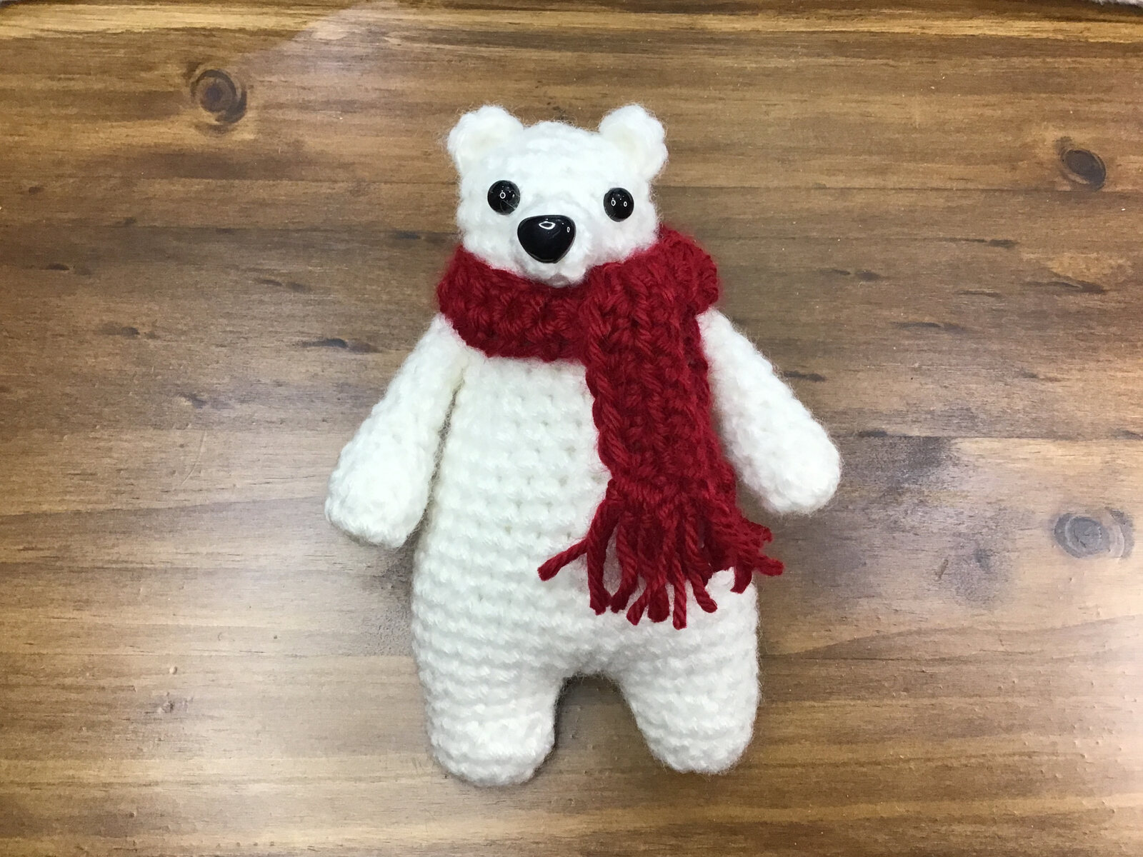 White crocheted polar bear wearing a red scarf