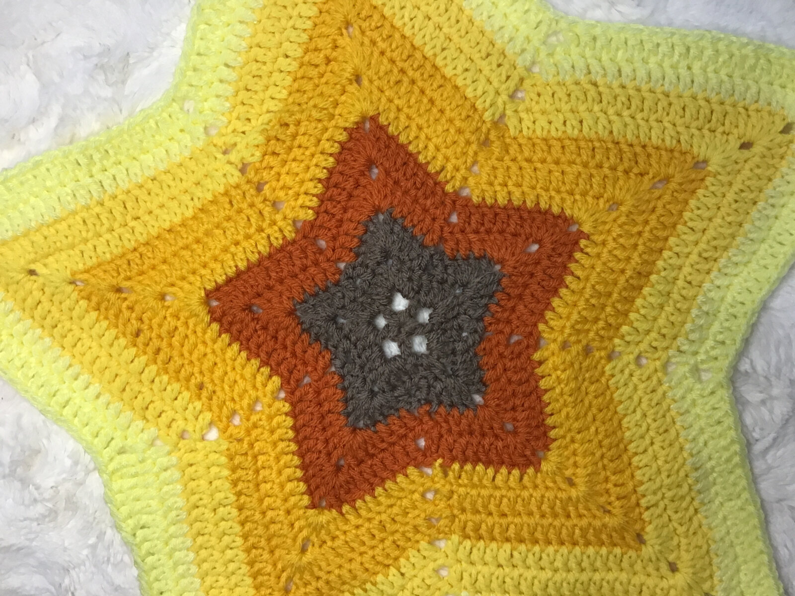 Crocheted star-shaped blanket in yellow, orange, and gray